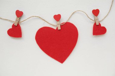 Mandallı ip ve beyaz grunge arka planda kırmızı kalpler. Sevgililer Günü kutlaması