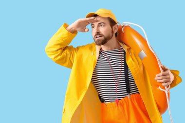 Mavi arka planda kurtarma yüzüğü olan bir erkek denizci.