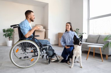 Tekerlekli sandalyedeki genç adam, karısı ve köpeğiyle taşınıyor.