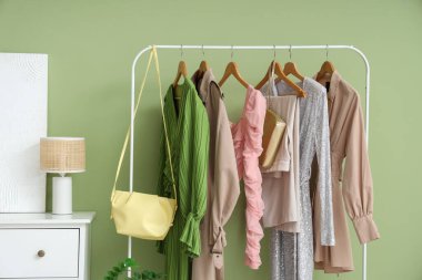 Soyunma odasındaki yeşil duvarın yanında giysiler ve çantalarla dizilin.