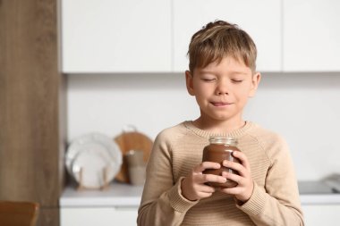 Mutfakta bir kavanoz çikolata ezmesi olan tatlı bir çocuk.