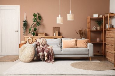 Oturma odasının içinde ekose ve pufla rahat bir kanepe.