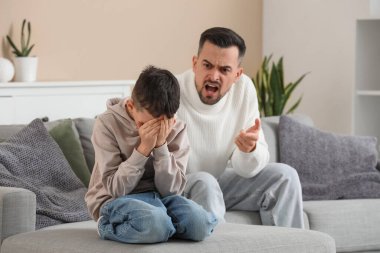 Baba ve oğlu evdeki kanepede didişiyor.