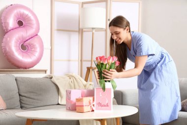 Kadınlar Günü 'nde evde vazoya lale koyan genç bir kadın.