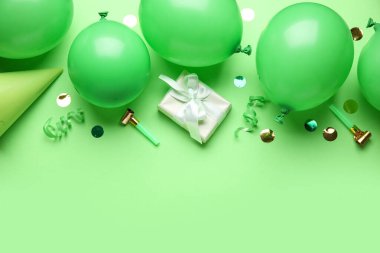Hediyeli balonlar, parti ıslıkları ve yeşil arka planda konfeti.