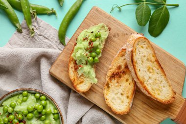 Turkuaz arka planda bezelye püresi ve ekmek dilimleri olan bir kase.