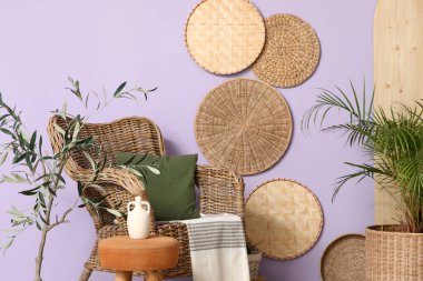 Hasır koltuk ve şık dekorasyon oturma odasındaki leylak duvarda.