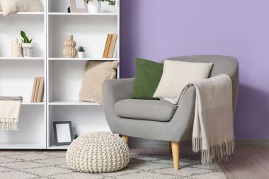 Gri koltuklu, puf ve kitaplıklı şık bir oturma odası.