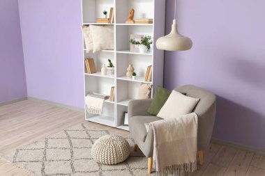 Gri koltuklu, puf ve kitaplıklı şık bir oturma odası.