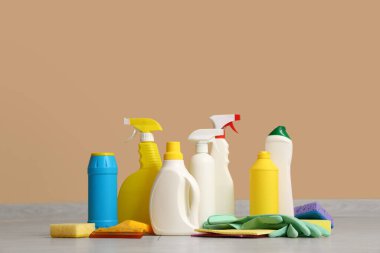 Bej duvarın yanındaki zeminde farklı temizlik malzemeleri var.