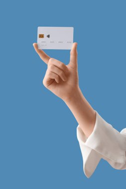 Mavi arka planda kredi kartı olan bir kadın.