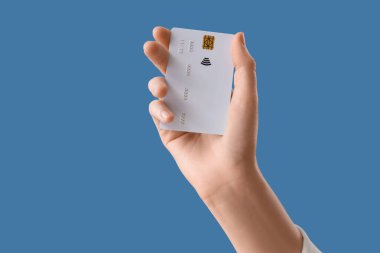 Mavi arka planda kredi kartı olan bir kadın, yakın plan.