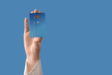 Mavi arka planda kredi kartı olan bir kadın.