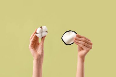 Yeşil arka planda tekrar kullanılabilir ped ve pamuk çiçeğini tutan kadın eller, yakın plan