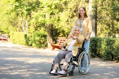 Tekerlekli sandalyedeki yaşlı kadın dışarıdaki bakıcı ile ilgili bir şeyi işaret ediyor.
