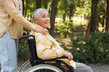 Dışarıda bakıcısı olan tekerlekli sandalyedeki son sınıf kadın.