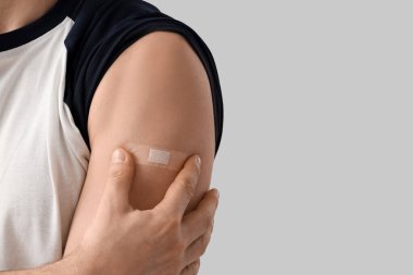 Aşıdan sonra hafif arka planda uygulamalı tıbbi yaması olan genç adam, yakın plan.