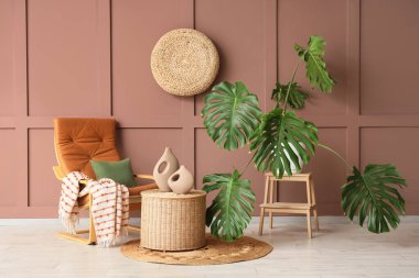 Monstera bitkisi, koltuk ve sepeti olan bir oturma odası.