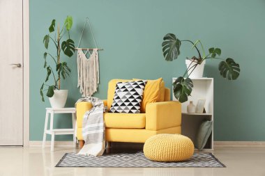 İçinde Monstera bitkileri, sarı koltuk ve raf ünitesi olan bir oturma odası.