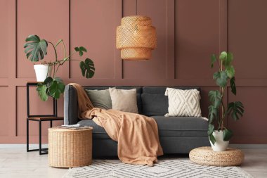 İçinde Monstera bitkileri, kanepe ve sepet olan bir oturma odası.