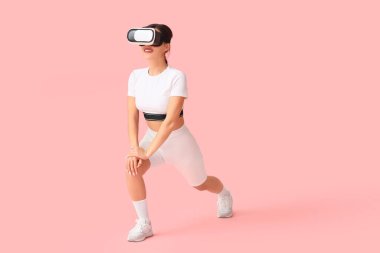 Modern VR gözlüklü genç bayan pembe arka planda egzersiz yapıyor.
