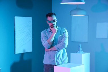 Sanat galerisinde VR gözlüklü düşünceli bir genç adam.