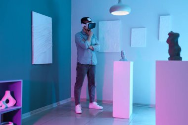 Sanat galerisinde VR gözlüklü düşünceli bir genç adam.