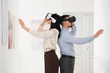 Sanat galerisinde VR gözlük kullanan genç bir çift.