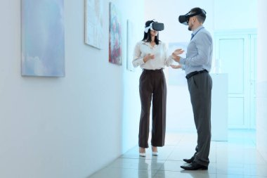 Sanat galerisinde konuşan gözlüklü genç bir çift.