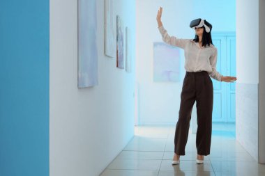 Sanat galerisinde VR gözlük kullanan genç bir kadın.