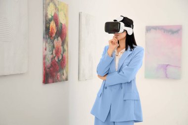 Sanat galerisinde VR gözlüklü düşünceli genç bir kadın.
