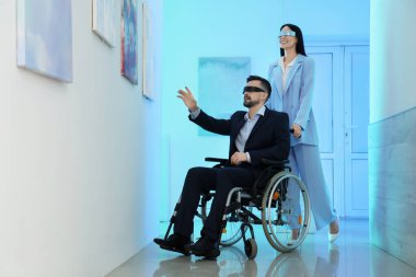 Sanat galerisindeki tabloların yanında VR gözlüklü genç çift.
