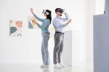Sanat galerisinde VR gözlük kullanan genç bir çift.
