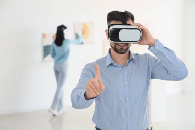 Sanat galerisinde VR gözlük kullanan genç adam.
