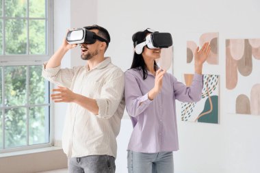 Modern sanat galerisinde VR gözlük kullanan genç bir çift.
