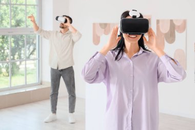 Modern sanat galerisinde VR gözlüklü genç bir kadın.
