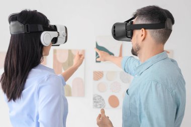 Sanal gerçeklik gözlüklü genç bir çift modern sanat galerisinde resimlere bakıyor.