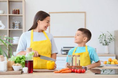 Genç anne ve oğlu mutfakta dolmalık biber kesiyorlar.
