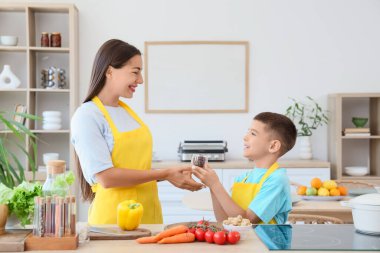 Genç anne ve oğlu mutfakta yemek pişiriyor.