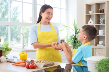 Genç anne ve oğlu mutfakta yemek pişiriyor.