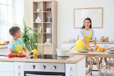 Genç anne ve oğlu mutfakta yemek pişiriyor.