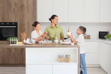 Genç anne ve çocukları mutfakta hamur hazırlıyorlar.