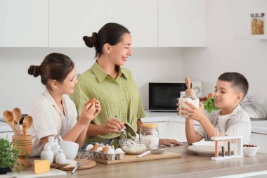 Genç anne ve çocukları mutfakta hamur hazırlıyorlar.