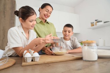 Genç anne ve çocukları mutfakta hamur hazırlıyorlar.