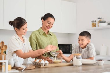 Genç anne ve çocukları mutfakta hamur hazırlıyorlar.