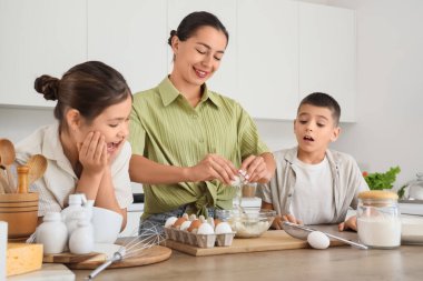 Genç anne ve çocukları mutfakta hamur hazırlıyorlar.