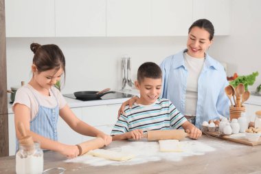 Genç anne ve çocukları mutfakta para saçıyor.