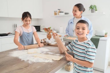 Genç anne ve çocukları mutfakta para saçıyor.