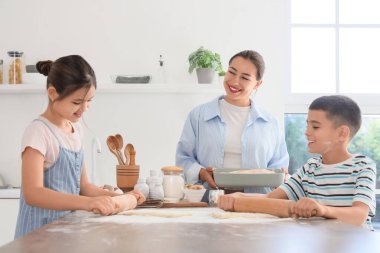 Genç anne ve çocukları mutfakta para saçıyor.