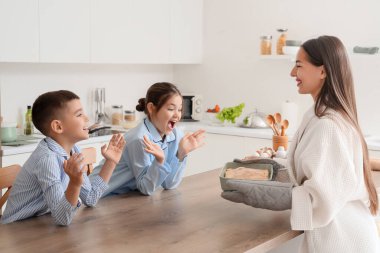 Lezzetli turtayla genç anne ve çocukları mutfakta.